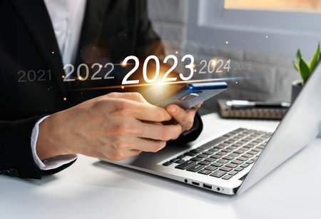 Asian businessman using mobile phone with virtual 2023 year diagram. Business planning, trend change from 2022 to 2023, goals, strategy, investment. Happy new year concept. Closeup and copy spaceの写真素材