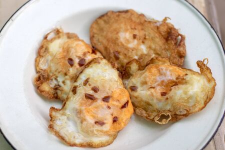 Fried egg on white plate with sauce.