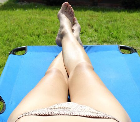womans body part in bikini during sunbath laying on deckchairの写真素材