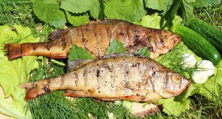 just having smoked perch, placed on a wooden tray with vegetableの写真素材