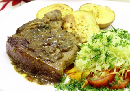 Grilled pork tenderloin with cranberry sauce on fried potatoes and vegetablesの写真素材