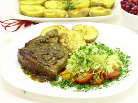 Grilled pork tenderloin with cranberry sauce on fried potatoes and vegetables の写真素材