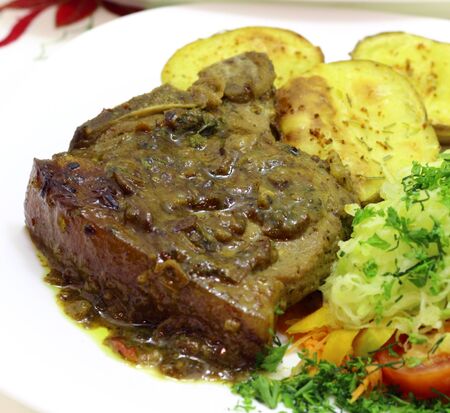 Grilled pork tenderloin with cranberry sauce on fried potatoes and vegetablesの写真素材