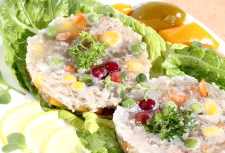 Pork with vegetables in jelly, served with lettuce leaves with lemon, pepperの写真素材