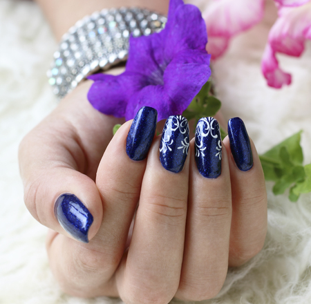 Beautifully manicured fingernails with flowers in the backgroundの写真素材