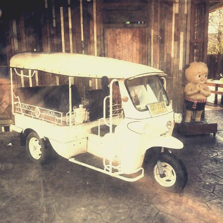 A withe Tuk-tuk in wood black ground.