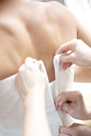 Two people working on a zipper of a brides dressの写真素材