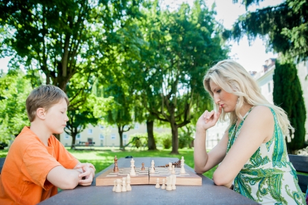 Mother and son playing chess in a parkの写真素材