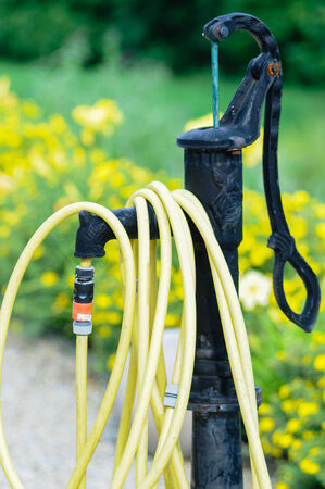 common home garden hose coiled up and hanging on a fountainの写真素材