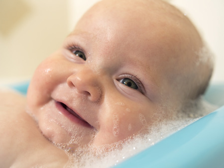 Close Up Face Shot of Infant Baby in Bubble Bath Smilingの写真素材
