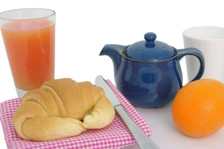 A light breakfast of tea, a croissant fruit juice and an orange. High key shot の写真素材