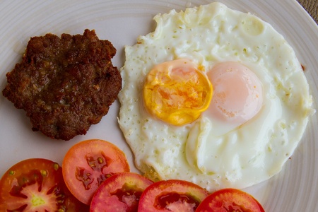 Fried pork with fried two eggs  and tomatoの写真素材