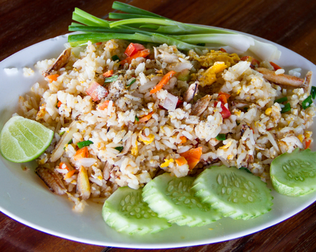 Fried rice with crab meat in white dish placed on a wooden table.の写真素材