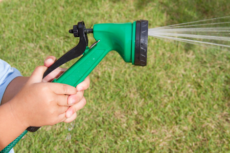 little boy water the plants with a spray nozzleの写真素材