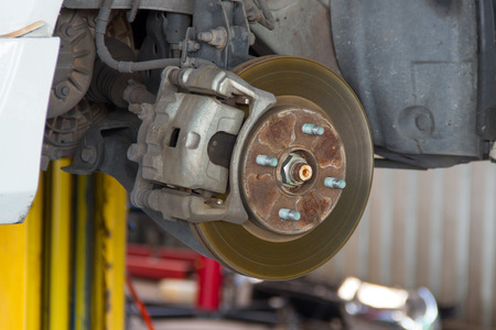 Front disc brake on car in process of new tire replacementの写真素材