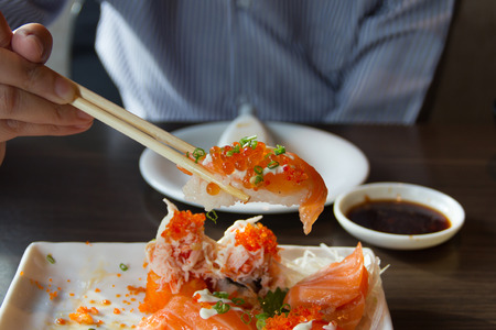People use chopsticks to pick up sushi.の写真素材