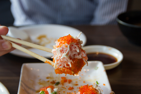 People use chopsticks to pick up sushi.の写真素材