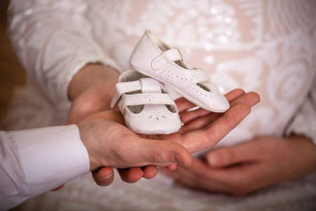 young couple holding small baby shoes in their handsの写真素材