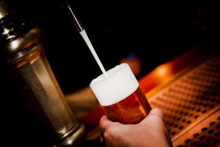 hand of bartender at the brewery pouring a draft beer into a glass serving in a restaurant or pub