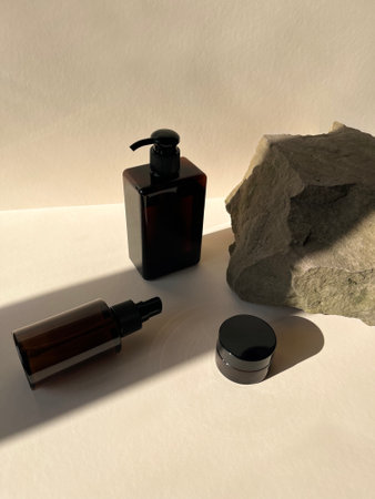 Glass brown jar with body lotion, jar with face cream, hair spray on beige background. organic moisturizing productsの写真素材