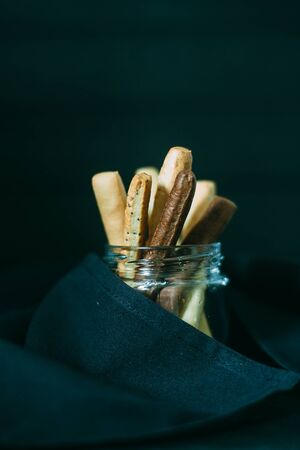 Grissini in a glass jar with black cloth on a dark backgroundの写真素材