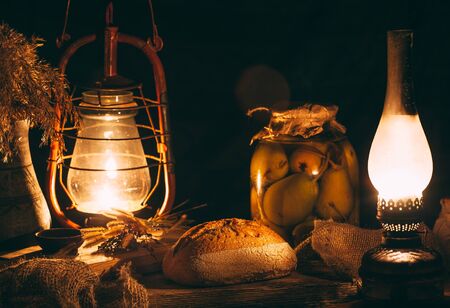 Homemade baked bread on a wooden board in warm light from gas lamps. Rustic vintage surroundings