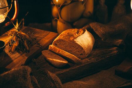 Pieces of sliced â€‹â€‹freshly baked bread in the light of candles. Bread on a wooden...
