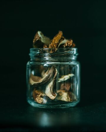 Slices of different dried mushrooms in a glass jar on a dark backgroundの写真素材