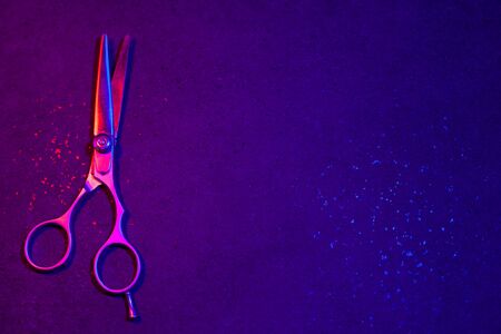Hairdressing scissors in neon light on a dark background. The tool of the hairdresser.の写真素材