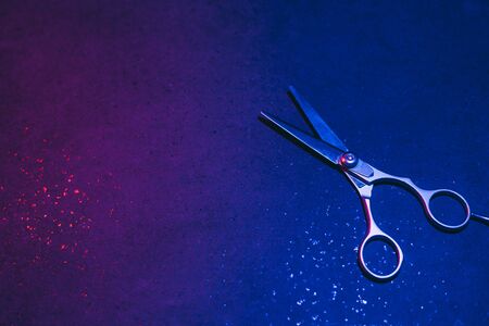 Hairdressing scissors in neon light on a dark background. The tool of the hairdresser.の写真素材