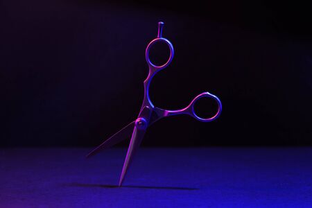 Hairdressing scissors in neon light on a dark background. The tool of the hairdresser.の写真素材