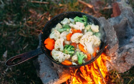 Cauliflower, broccoli and carrot in a pan. Cooking on an open fire. Outdoor food. Grilled vegetables. Food on a camping tripの写真素材
