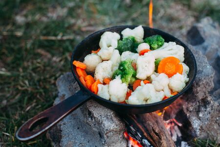 Cauliflower, broccoli and carrot in a pan. Cooking on an open fire. Outdoor food. Grilled vegetables. Food on a camping tripの写真素材