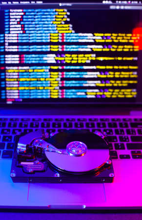 Hard drive on a laptop keyboard. Reflection of program code from the screen. Neon light. Programming...