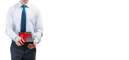 Business man holding a gift with a red ribbon. Guy on a white background in a light shirt with a...