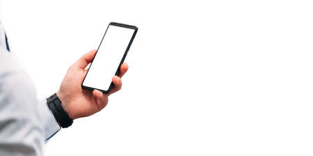 A business man in a shirt holds a phone with a white screen on a white background. Narrow panoramic...