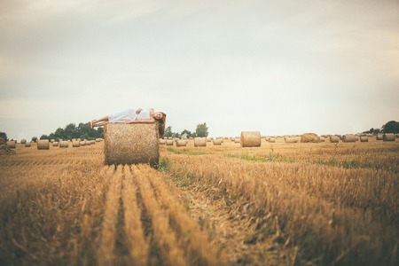 Beautiful Girl on Hay Bales in the Fieldsの写真素材