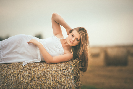 Beautiful Girl on Hay Bales in the Fieldsの写真素材