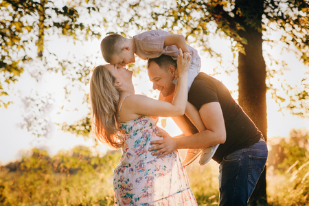Happy young family waiting for a baby in a parkの写真素材