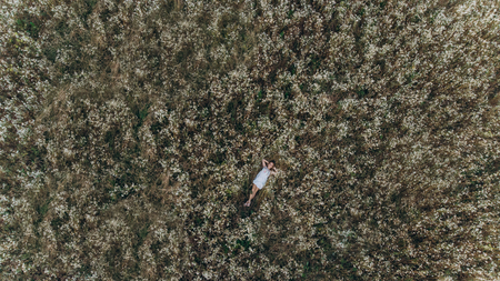 Aerial TOP view of a girl lying in a flower field and relaxingの写真素材