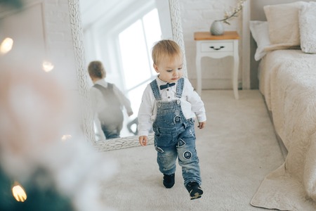 Stylish boy in a denim suit and a butterfly looking at the New Years room