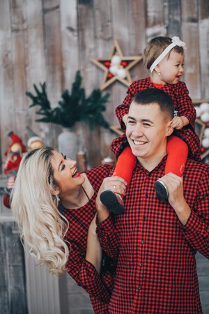 Happy Family with his little daughter together in decorated holidays room with a Christmas tree and a wreath on the backgroundの写真素材