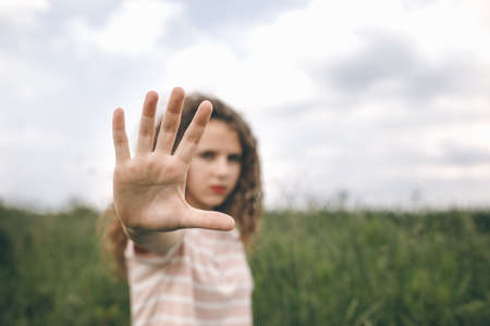 A Young Girl Standing On A Field And Show Stop Hand. Cloudy day. Blurred backgroundの写真素材