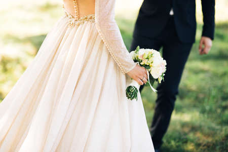 Bride holding her wedding flower bouquet. Wedding couple hugging, the bride holding a bouquet of flowers in her handの写真素材