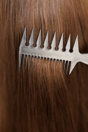 Close up of haircare, comb moves along beautiful healthy long flowing brown hair, texture. Healthy long smooth flowing brown hairの写真素材