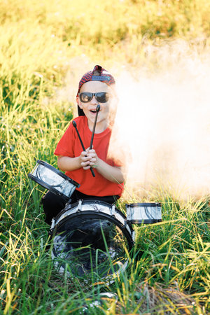 Smiling drummer boy beat drumstick in hard rock music. Young boy practice playing instrument drums. Teenager rock band drummer. Concept of music learning, happy relaxing timeの写真素材