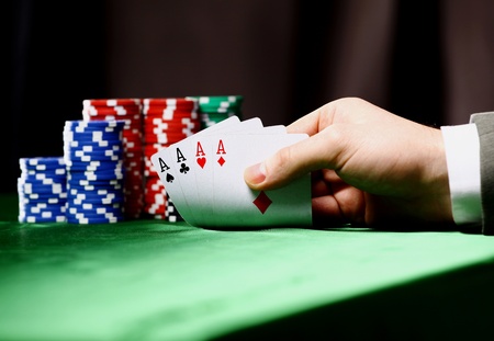 Poker chips and a hand flip the cards isolated against green felt