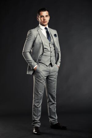 Handsome young business man standing on black backgroundの写真素材