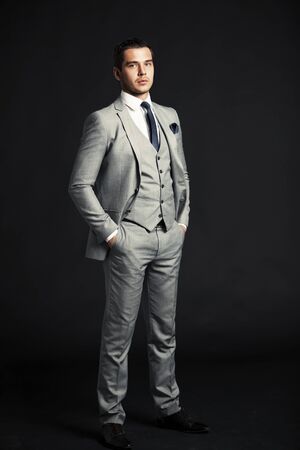 Handsome young business man standing on black backgroundの写真素材
