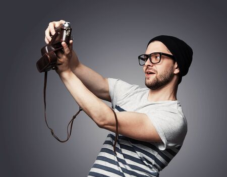 I love selfie! Handsome young man in shirt holding camera and making selfie and smiling while standing against grey backgroundの写真素材